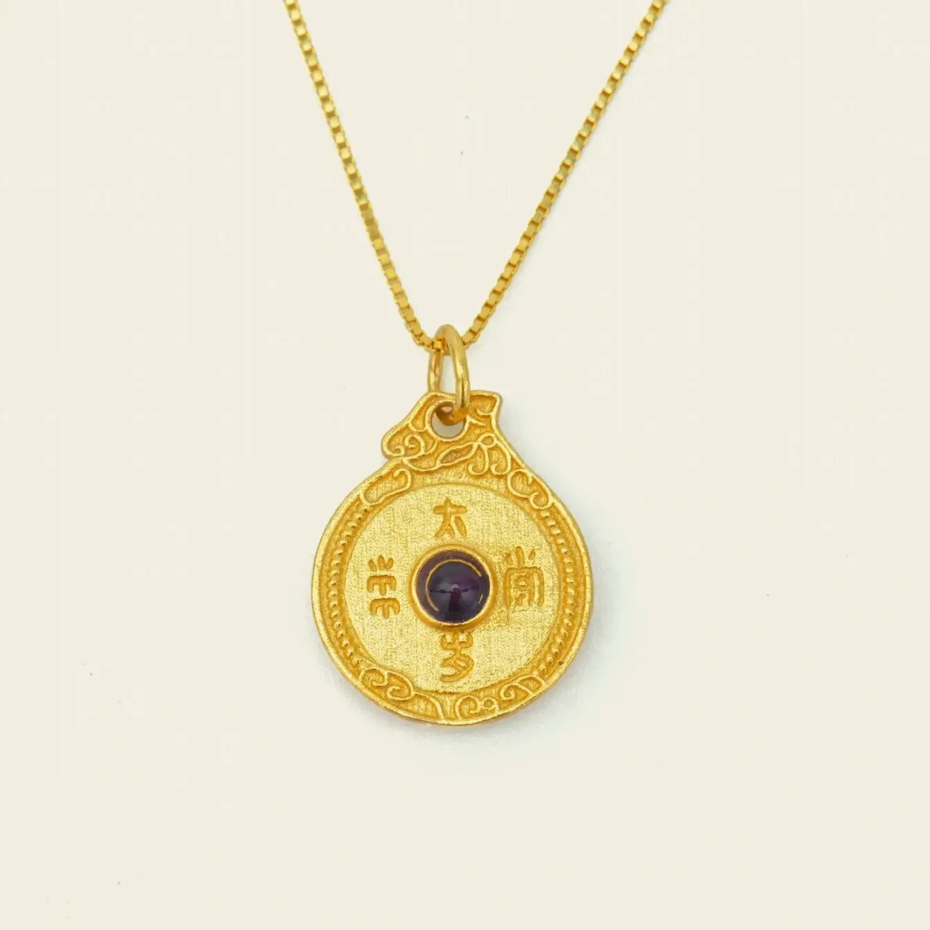 Circle of Harmony Necklace featuring a gold pendant with a central gemstone and intricate engravings.