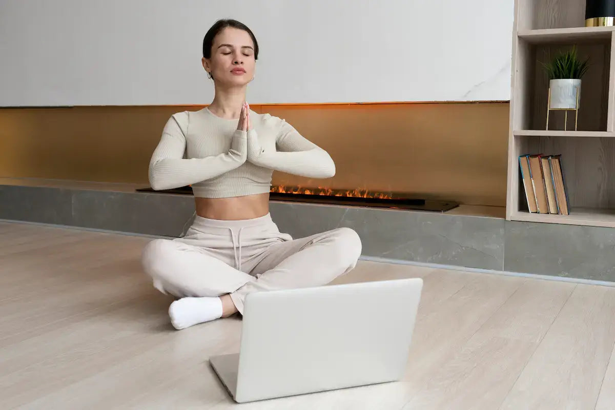 Woman practicing mindfulness while learning about why some people are more prone to stress with a laptop.