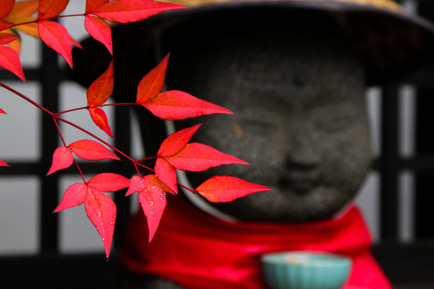 A serene stone statue with red maple leaves, symbolizing the Wisdom of Sutras and self-reflection.