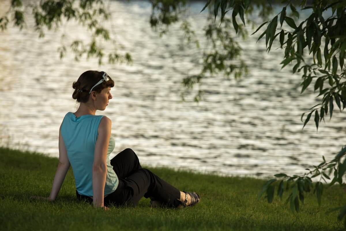 A woman meditating by the water, reflecting on The Power of Meditation for personal renewal.