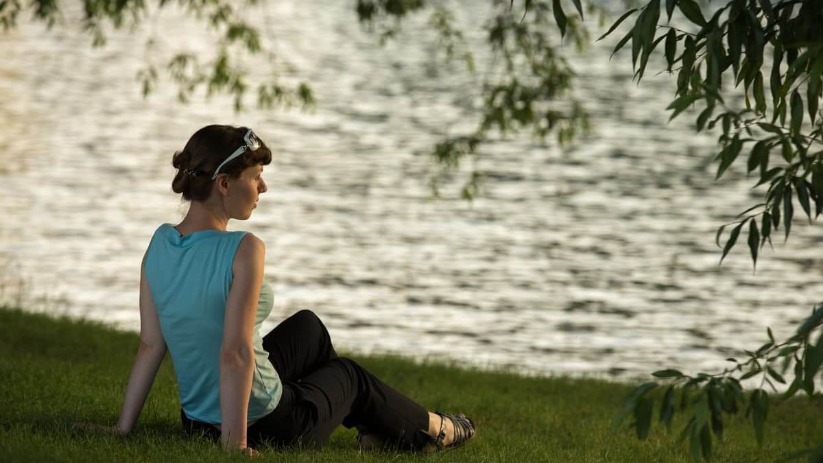 A woman meditating by the water, reflecting on The Power of Meditation for personal renewal.