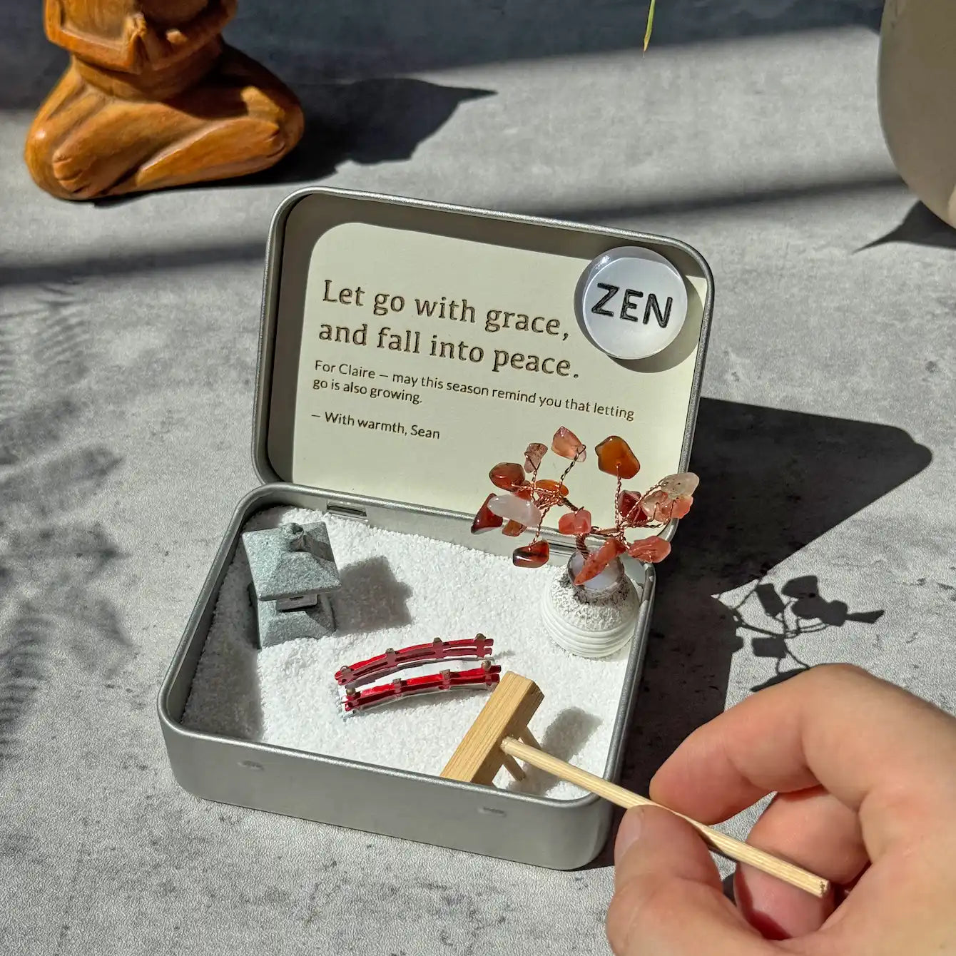 The Psychology Behind Zen Gardens and Focus: miniature zen garden arrangement with decorative stones and a rake.