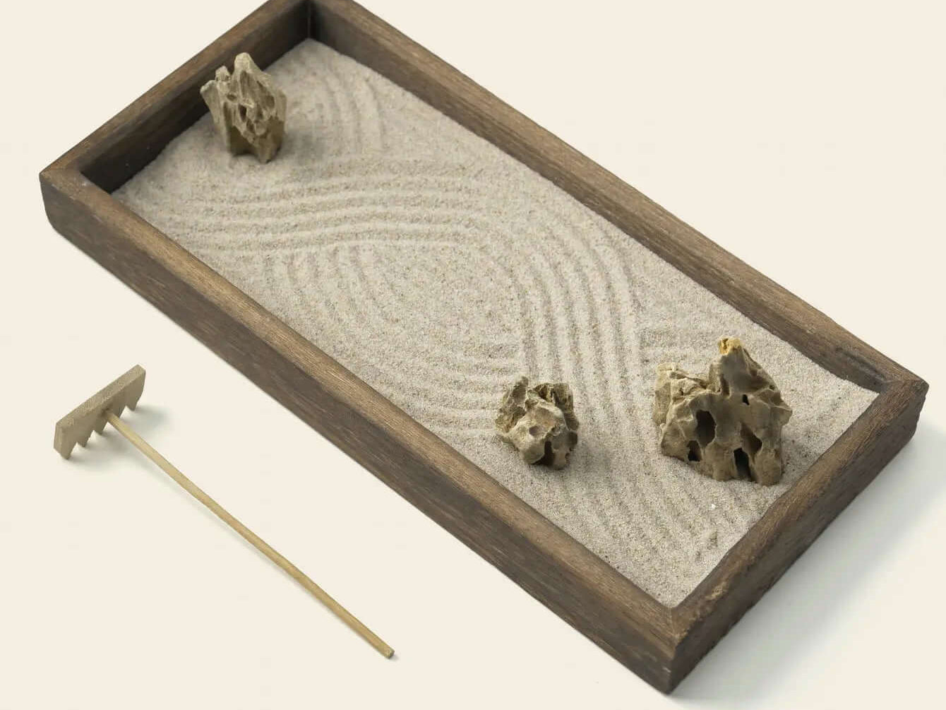 Parallel lines raked through white sand around natural stones in a Zenify karesansui garden