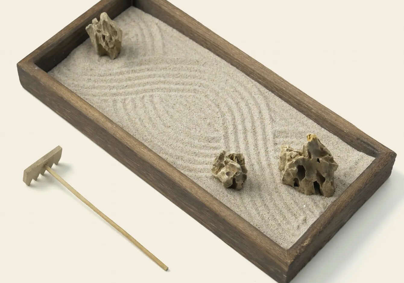 Parallel lines raked through white sand around natural stones in a Zenify karesansui garden