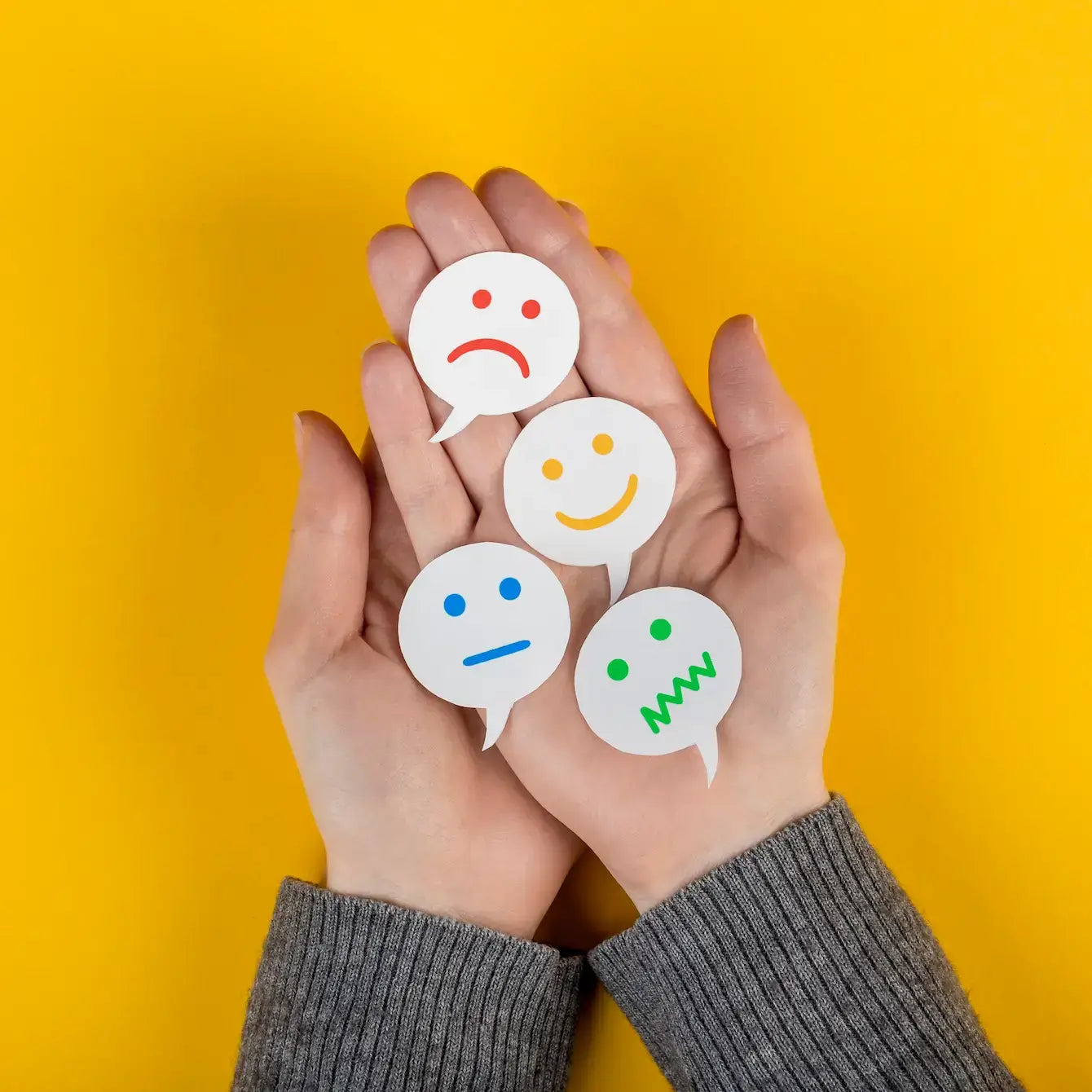 Hands holding various emotion symbols representing feelings to help make peace with the world.