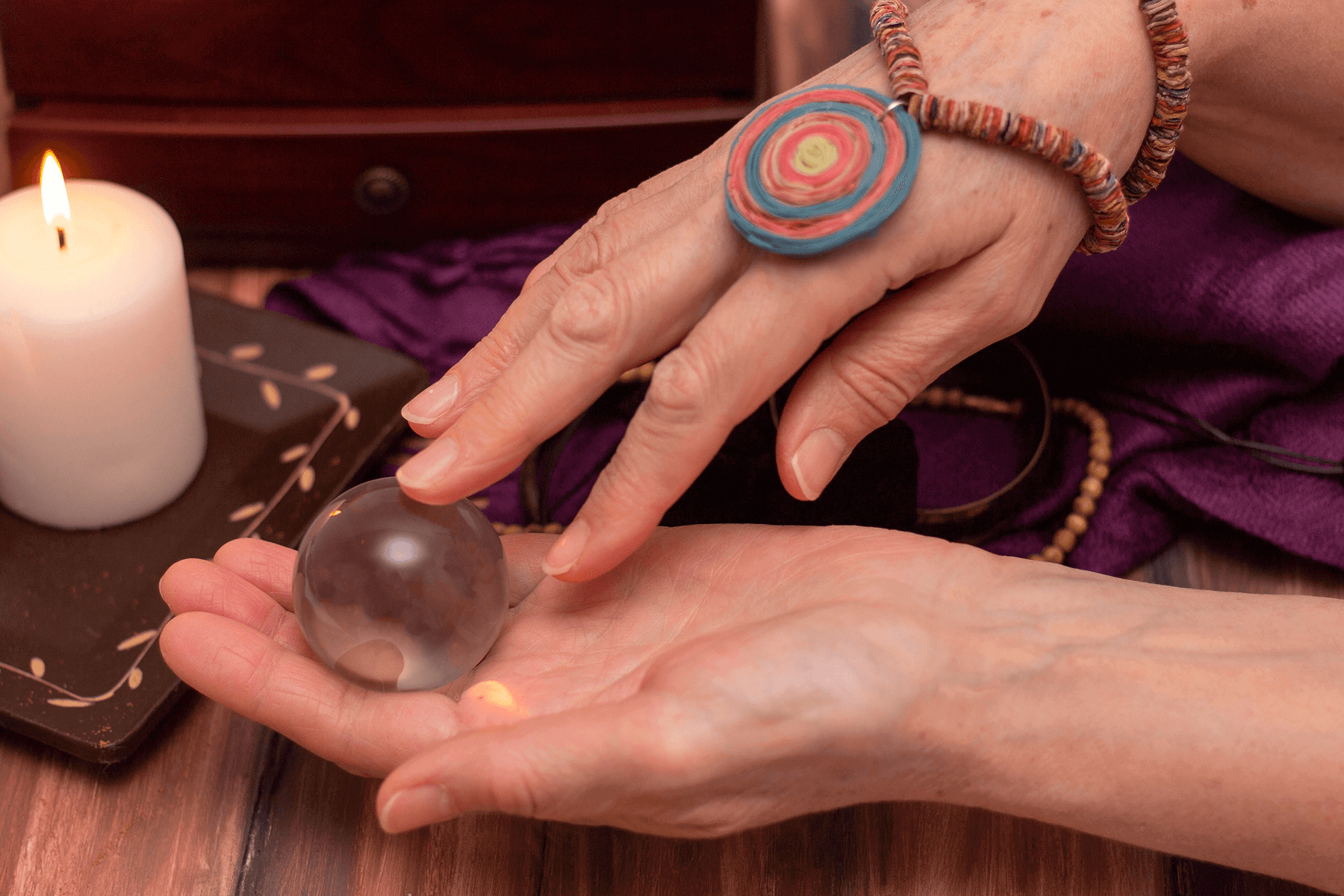 A person practicing meditation with a crystal ball and candle, illustrating why crystals enhance meditation.
