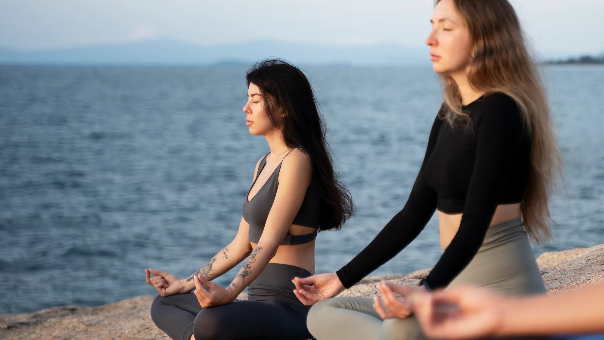 Women meditating by the water during World Meditation Day 2025, promoting mindfulness and relaxation.