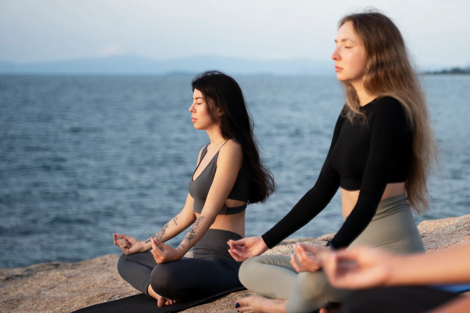 Women meditating by the water during World Meditation Day 2025, promoting mindfulness and relaxation.