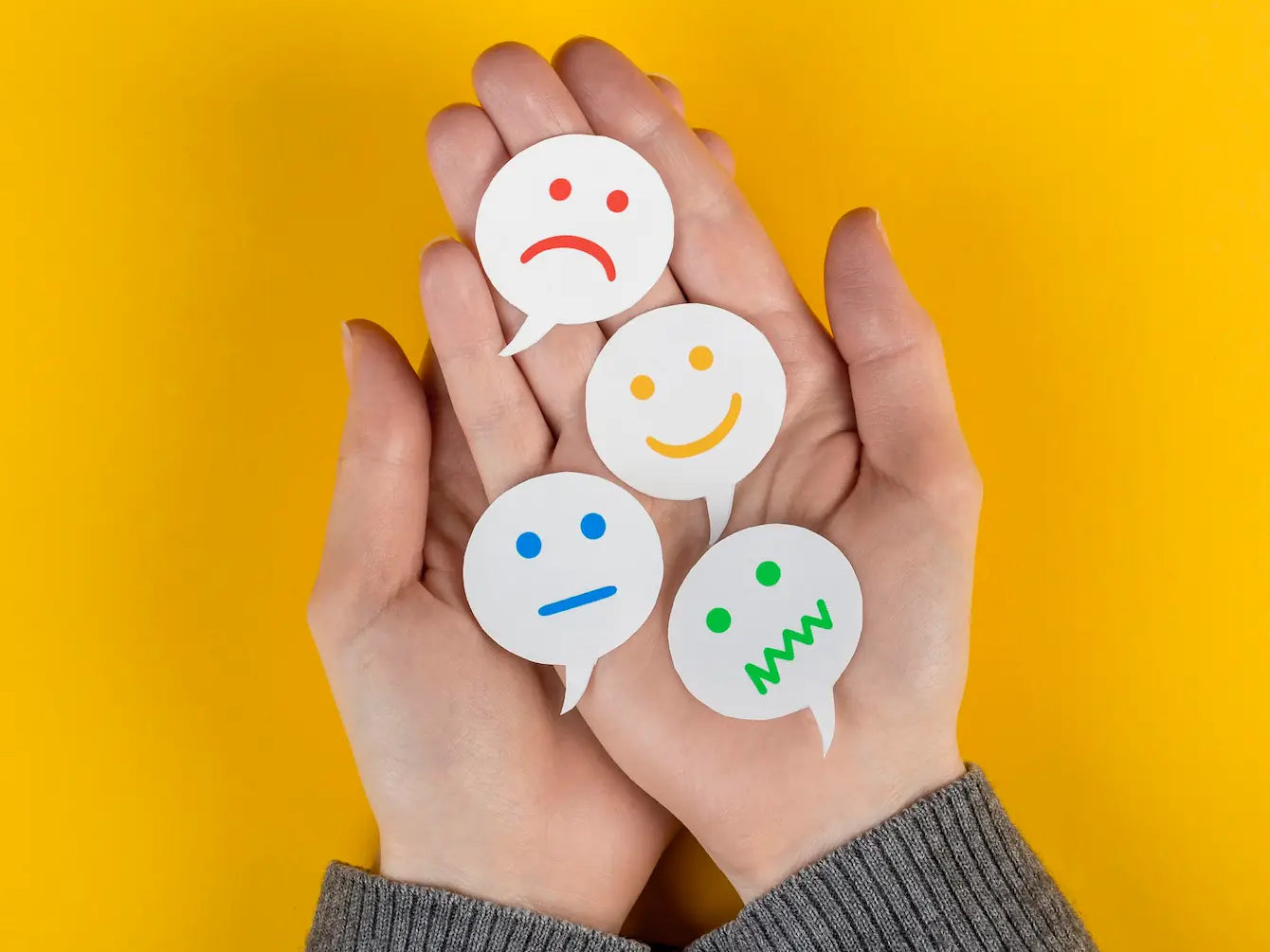 Hands holding various emotion symbols representing feelings to help make peace with the world.