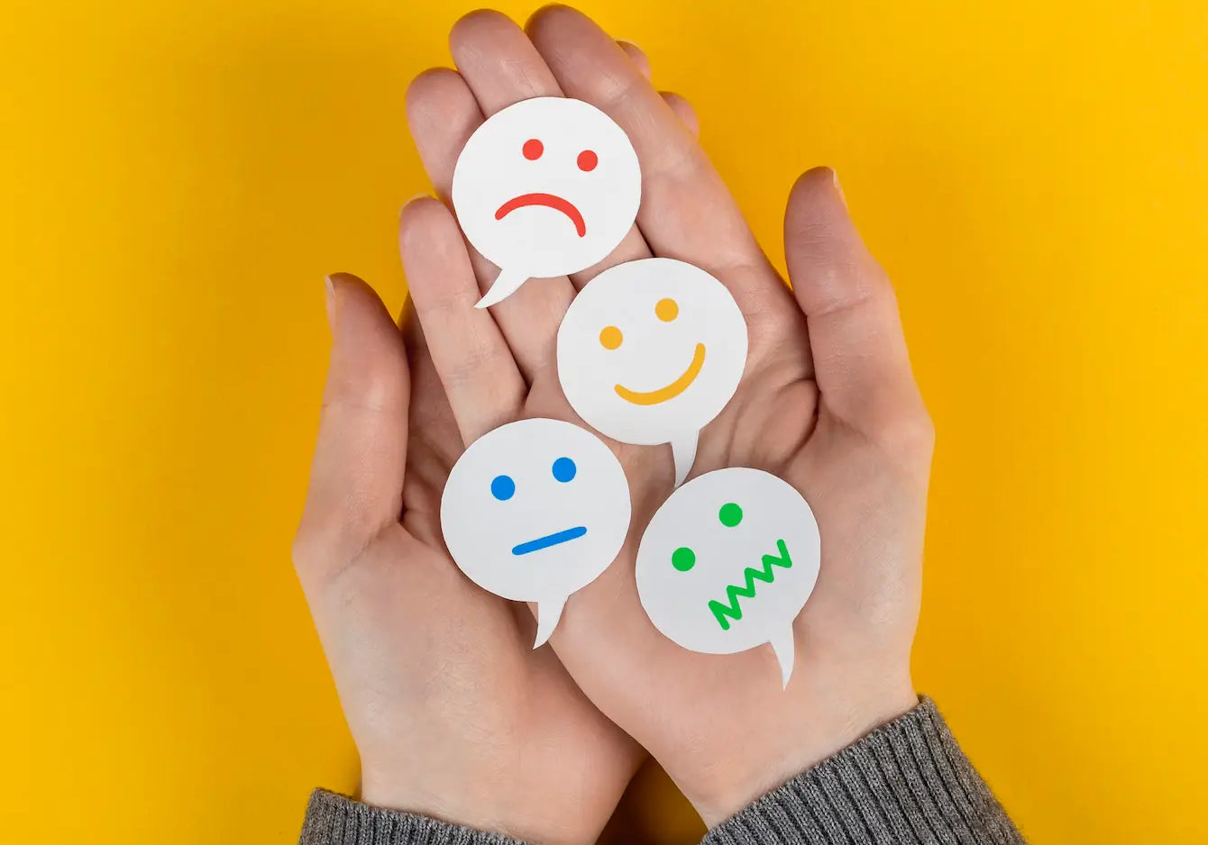 Hands holding various emotion symbols representing feelings to help make peace with the world.