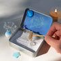 Person arranging the Pisces Crystal Zen Garden with aquamarine tree, blue aventurine star, and white sand.