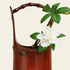 Handcrafted bamboo flower vase with white flowers and green leaves, perfect for a tranquil home decor.