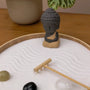 Zen Garden with a small Buddha statue and stones, promoting calm and clarity in mindfulness practice.