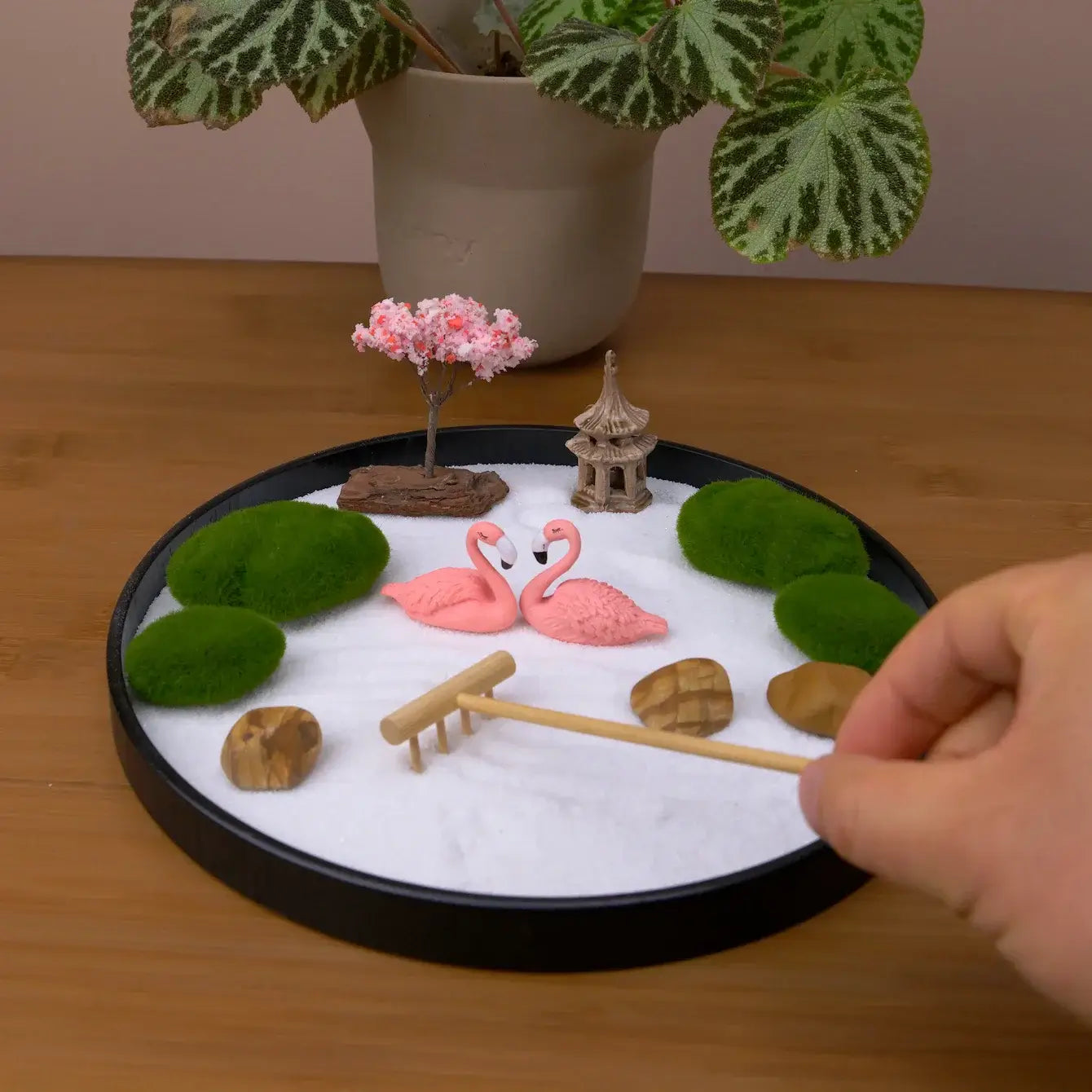 Zen Garden with pink flamingos, a cherry blossom tree, and decorative stones for tranquility and whimsy.