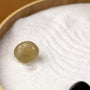 Zen Garden featuring a smooth, greenish stone resting on white sand with gentle patterns for tranquility and relaxation.