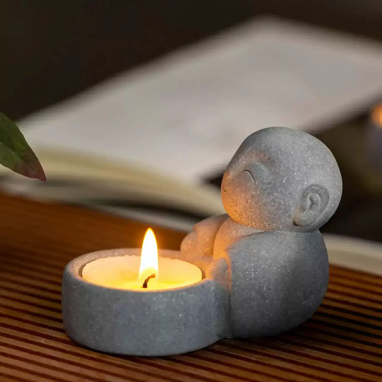 Zen-Stone Jizo Monk Cement figurine holding a small candle, creating a serene atmosphere.