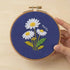 Close-up of 5-Hour Mindfulness Embroidery Kit with daisies on blue fabric, showcasing the floral design and craftsmanship.