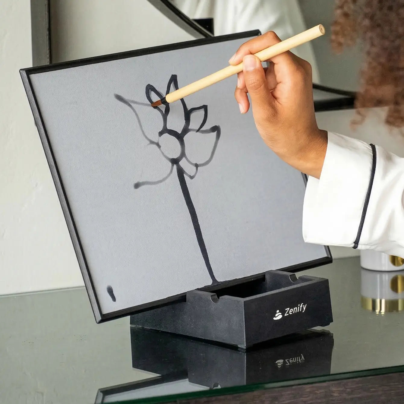 Person using a brush on the Flow Water Painting Board to create a flower drawing.