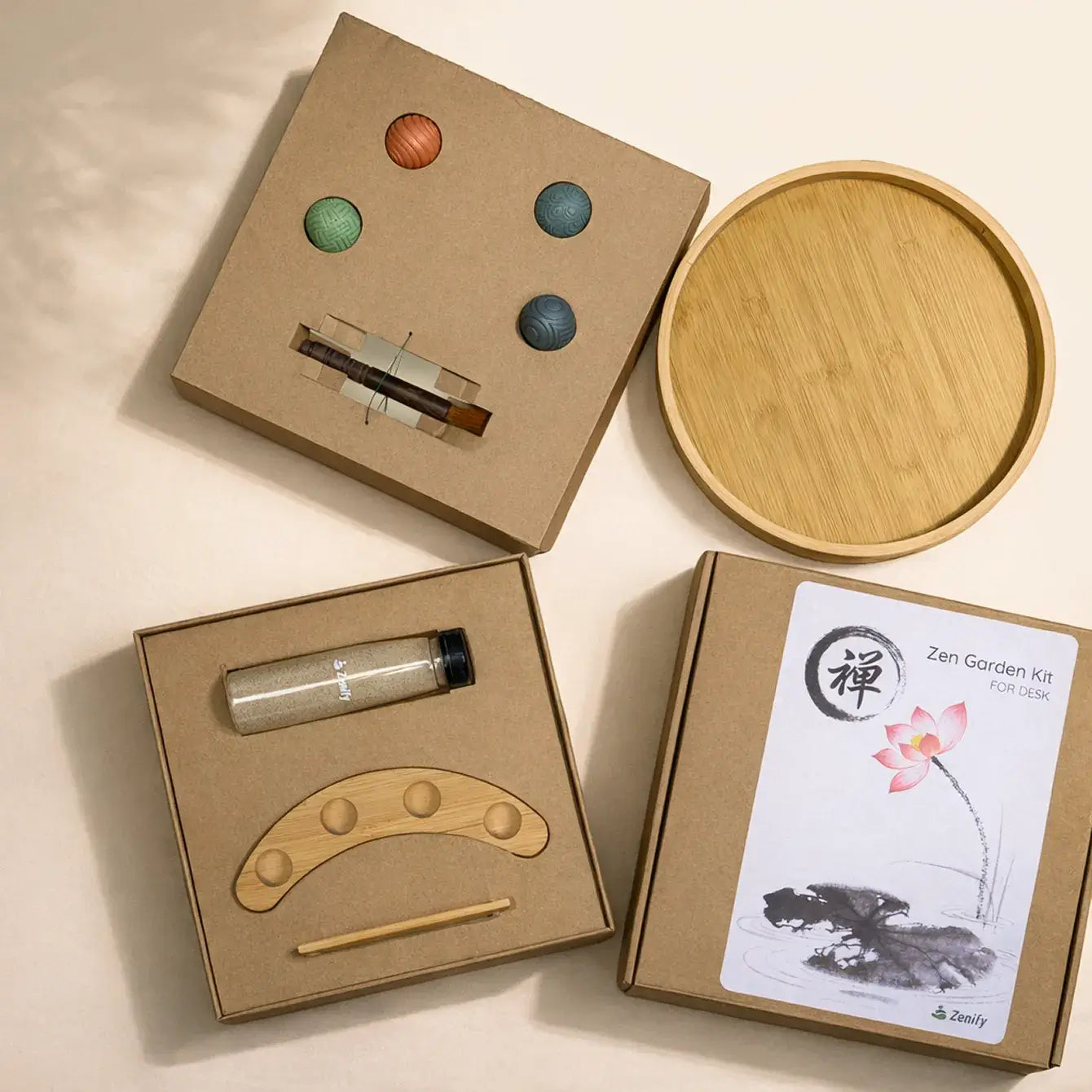 Opened Four Elements Zen Garden packaging with round bamboo tray, four textured resin spheres, sand bottle, bamboo rake, wood brush and sphere holder.