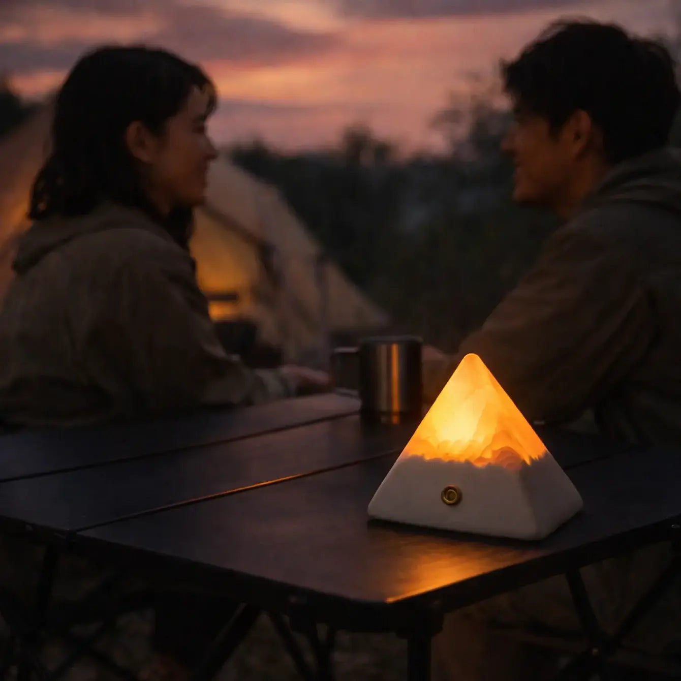 Cozy scene of a couple enjoying a Mineral Pyramid Stone Lamp while camping outdoors at dusk.