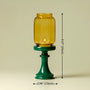 Yellow glass candle holder on a green stand with measurements indicated.