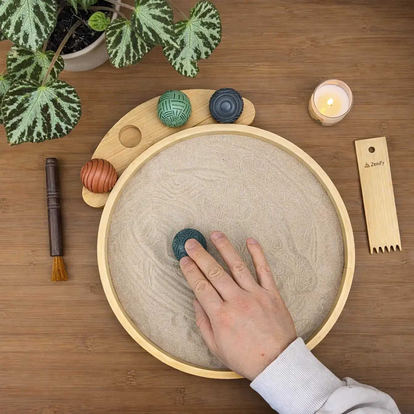 Person using a Desktop Zen Garden with bamboo sand tray and decoration stones for mindfulness and relaxation.