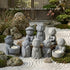 Zen-Stone Jizo monk cement figurine collection with candle holders displayed in a serene stone garden setting.