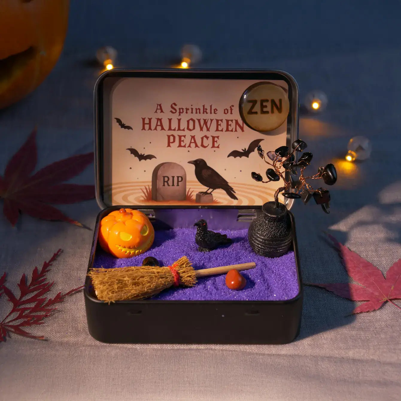 Zenify Halloween Obsidian Pocket Garden in a metal tin with mini pumpkin, raven, and broom for mindful gifting.