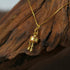 Zenify™ mantra wheel necklace pendant resting on natural wood background, showcasing intricate design and golden finish.