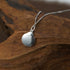 Close-up of the Zenify™ Zodiac Harmony Necklace featuring a Nine Palaces Bagua pendant on a textured wooden background.