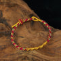 Zenify™ Fortune Knot – Handwoven Lucky Cord Bracelet in red and gold on wooden surface.