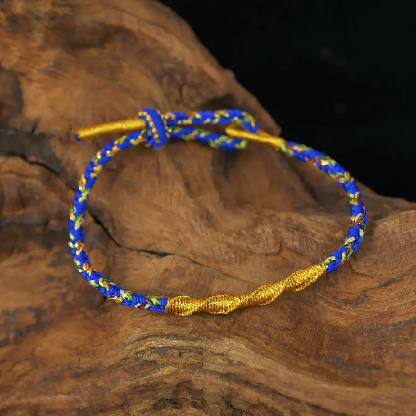 Zenify™ Fortune Knot – Handwoven lucky cord bracelet in blue and gold on wooden background.