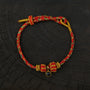 Zenify™ Sutra Light Knot – Handwoven blessing bracelet with red and gold threads and a black gemstone charm.