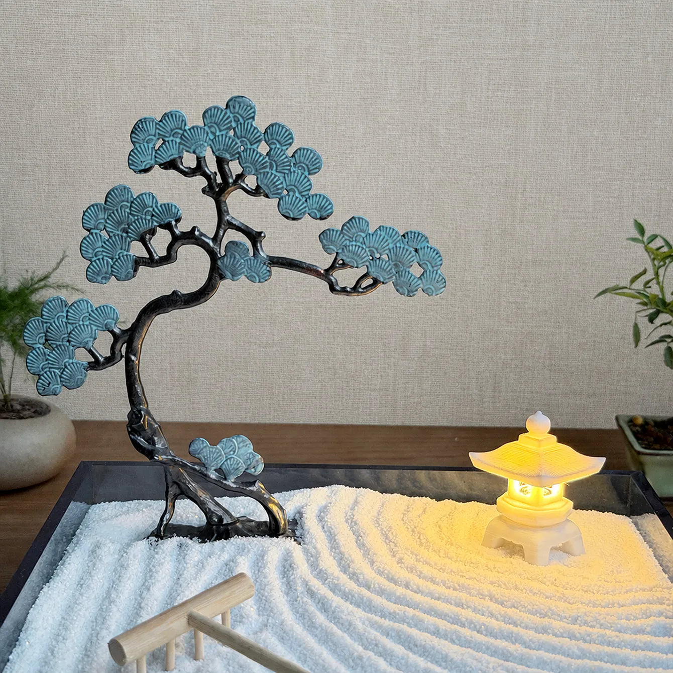 Copper blue pine tree and glowing resin stone lantern arranged in raked fine white sand