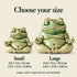 Small and large green ceramic meditation frogs with dimensions in centimeters and inches on a warm ivory background; each size is sold individually.