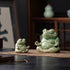 Small and large green glazed ceramic meditation frogs displayed together on a brown cloth; sold individually.