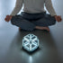 Person meditating with a glowing cube on the floor