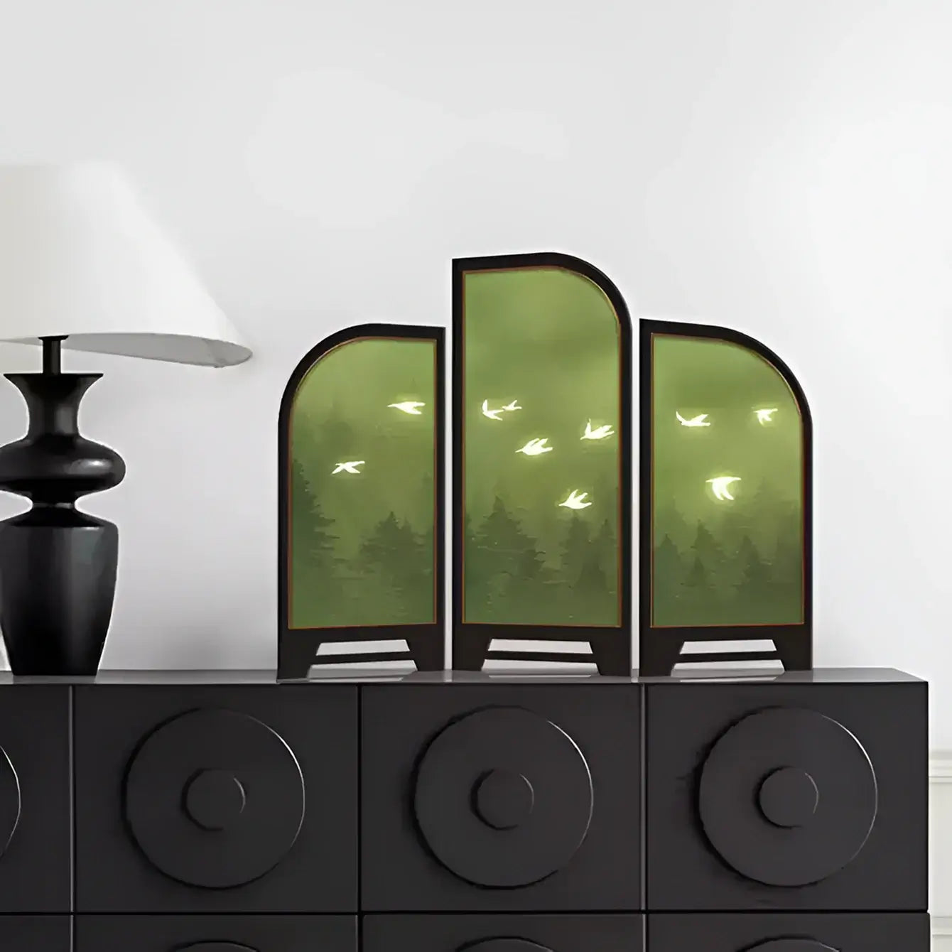 Decorative screen with nature design on a black cabinet against a white wall