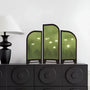 Decorative screen with nature design on a black cabinet against a white wall