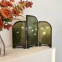Set of three green decorative screens on a white surface with flowers in the background