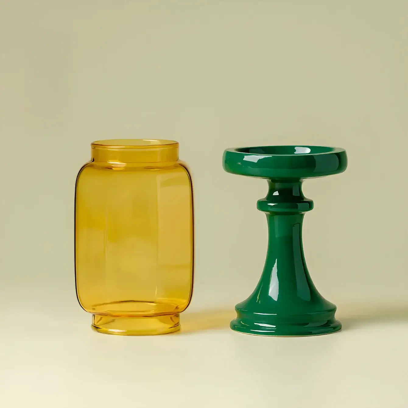 Yellow glass jar and green candle holder on a beige background