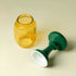Yellow glass jar and green and white candle holder on a beige background