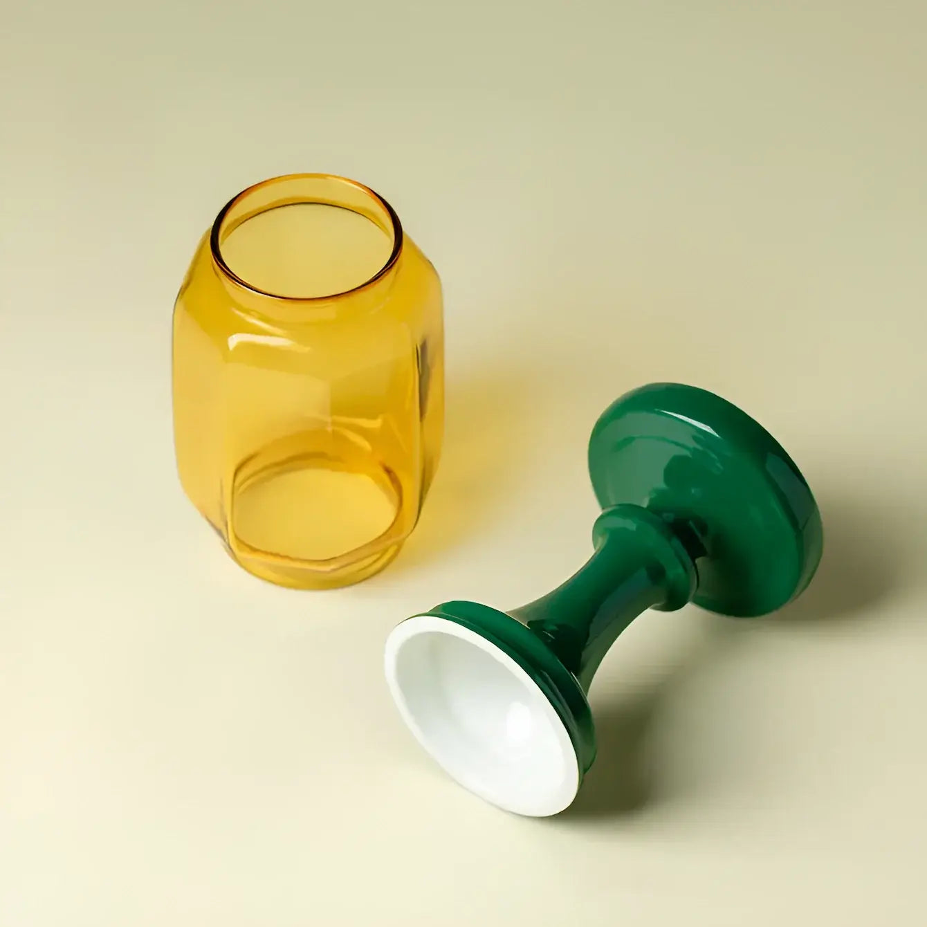 Yellow glass jar and green and white candle holder on a beige background