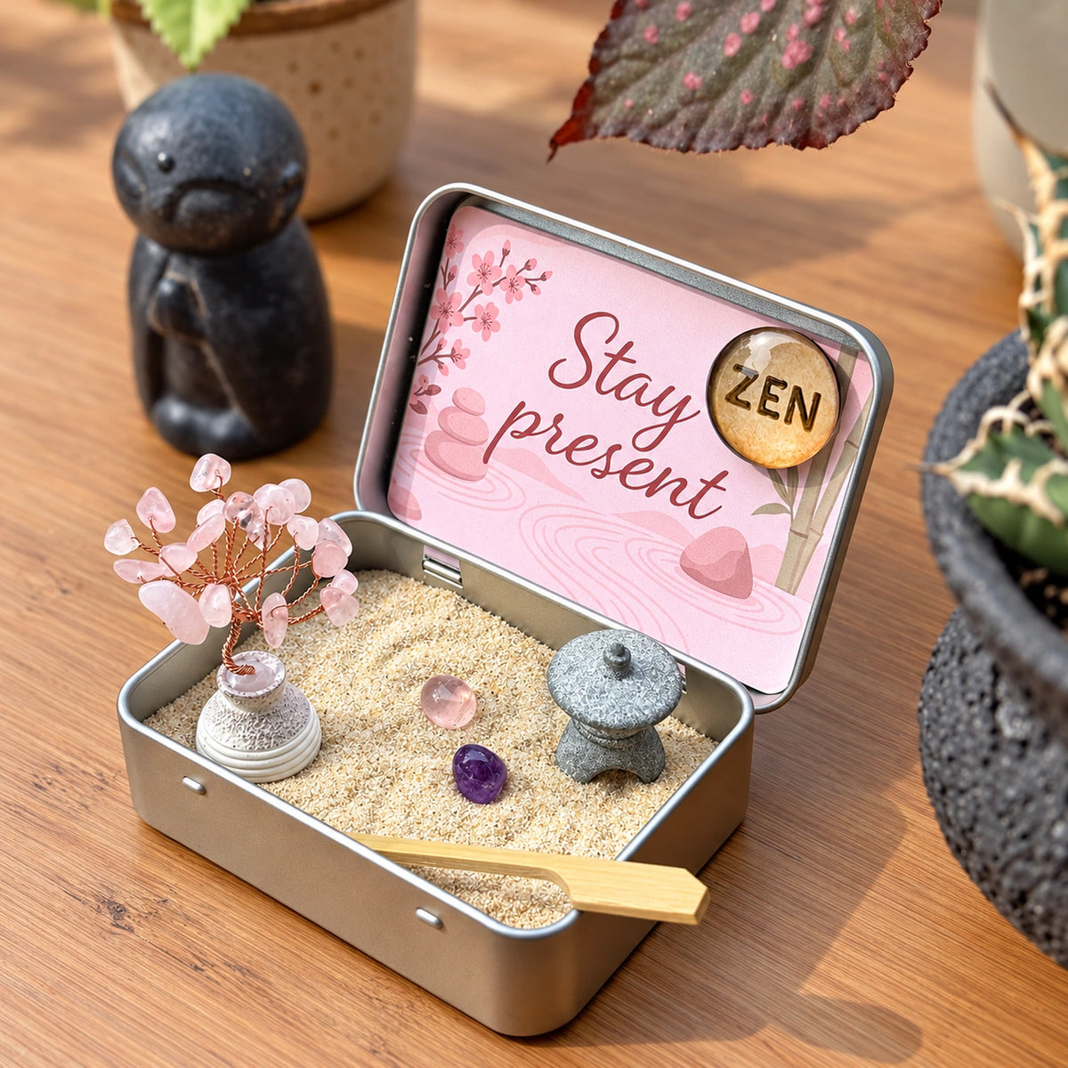 Open Japanese Crystal Zen Garden on a wooden table, with a rose quartz tree, pink and purple stones, gray lantern, bamboo tool, Stay present card and ZEN magnet.