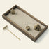 Angled close-up of the Japanese Karesansui Zen Garden with natural stones, raked white sand, dark wood tray, and wooden rake.