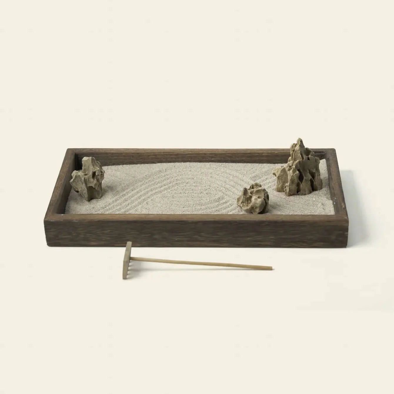 Japanese Karesansui Zen Garden with raked white sand, natural stones, dark wood tray, and wooden rake.