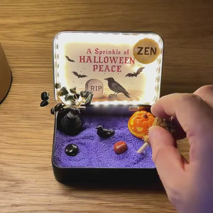 Hands gently tracing purple sand in the Light-Up Halloween Crystal Zen Garden; LED lighting is included with the Light-Up edition only.