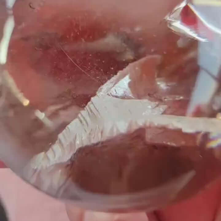 Close-up of a hand holding a clear quartz sphere showcasing internal patterns and reflections.