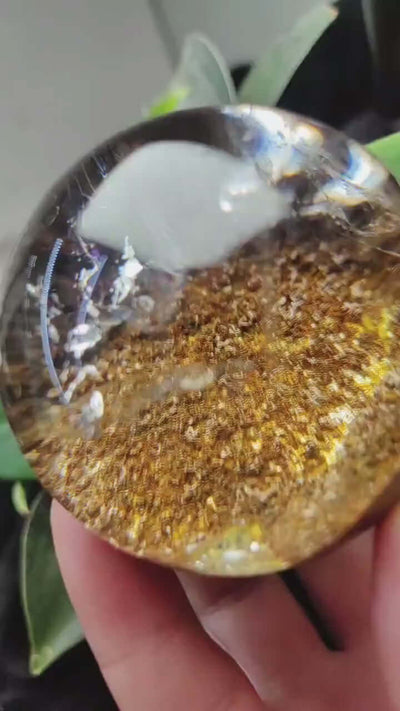 Zenify™ Phantom Quartz Sphere in hand, showcasing layered golden interior and unique phantom formations.