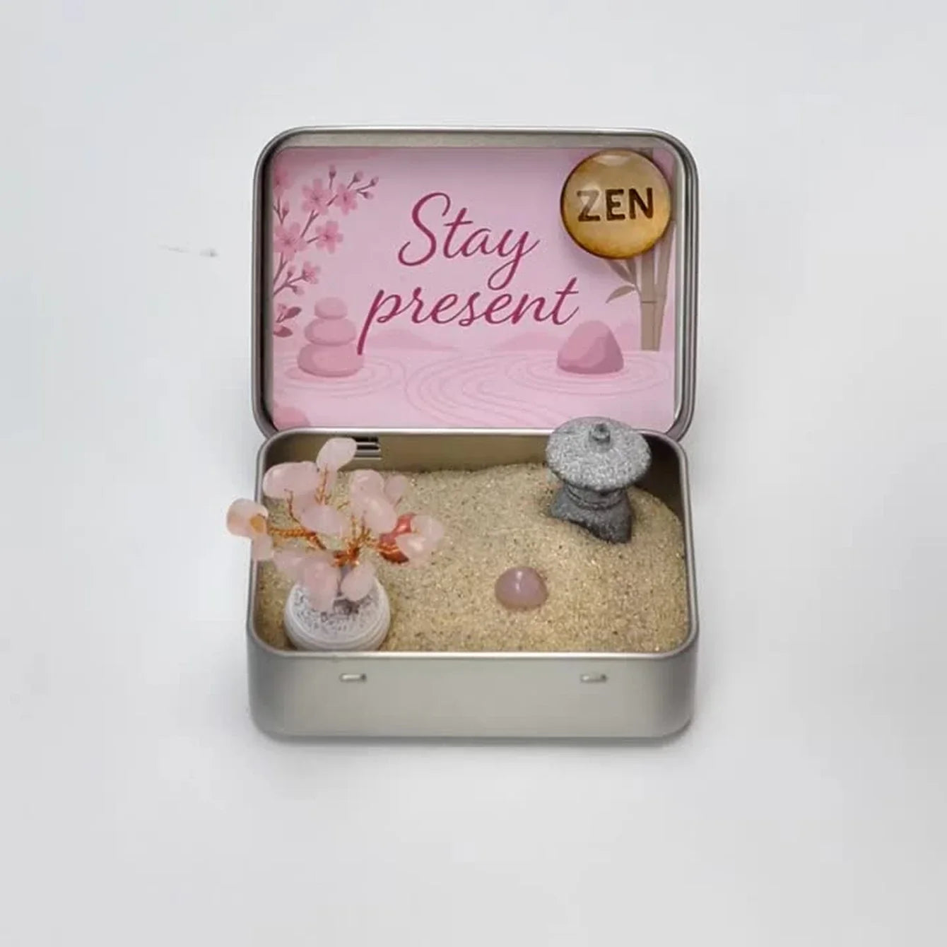 Hands setting up a Japanese Crystal Zen Garden, arranging its miniature pieces and tracing the sand with a bamboo tool.